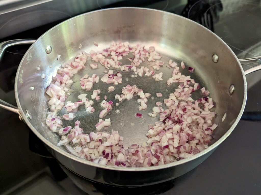 Shallots sautéing in butter in a pan.