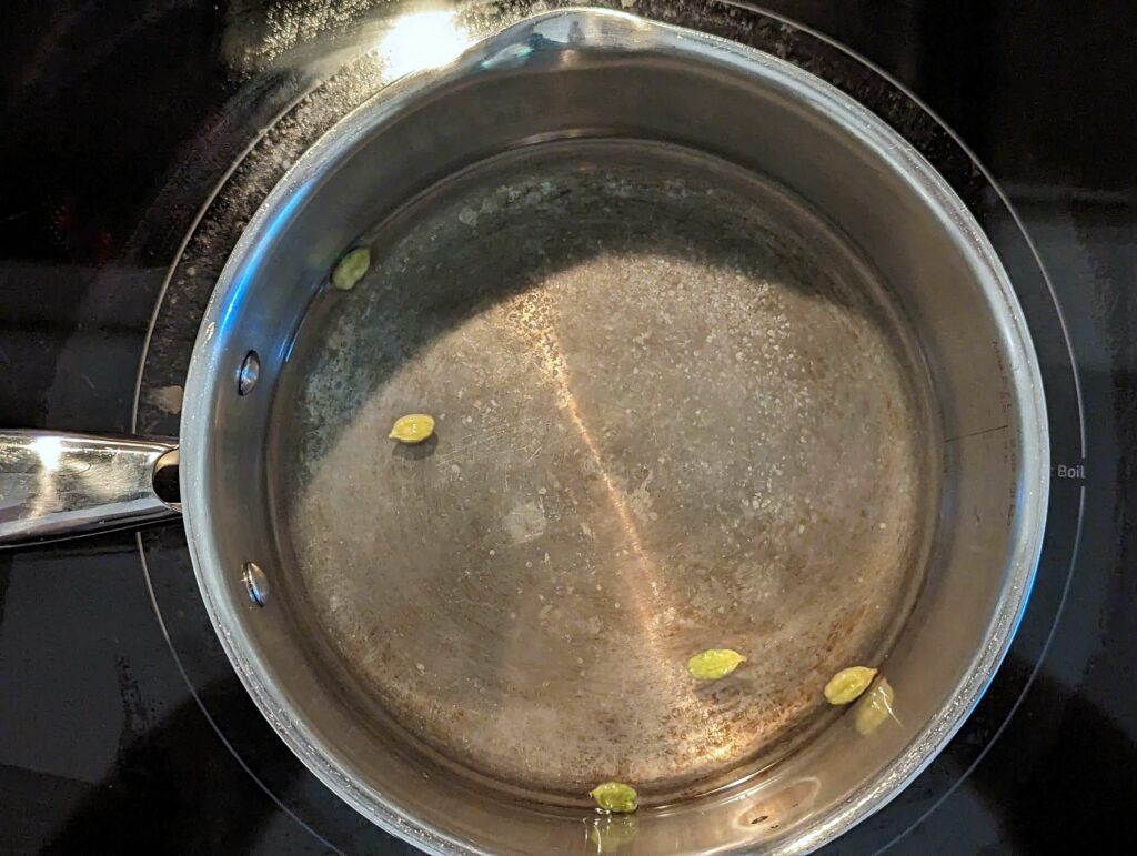 Water boiling with salt and whole cardamom.