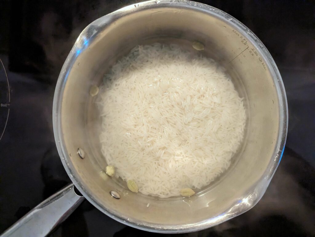 Rice added to the boiling water in a sauce pan.