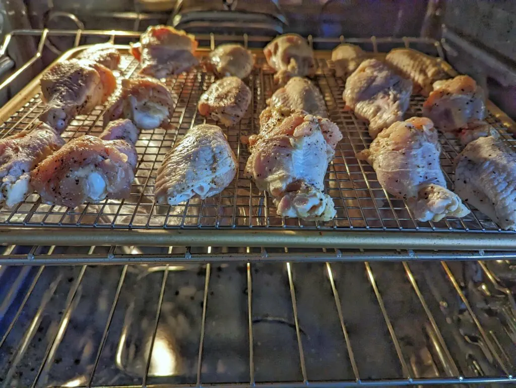 Wings roasting on a baking sheet in the oven.