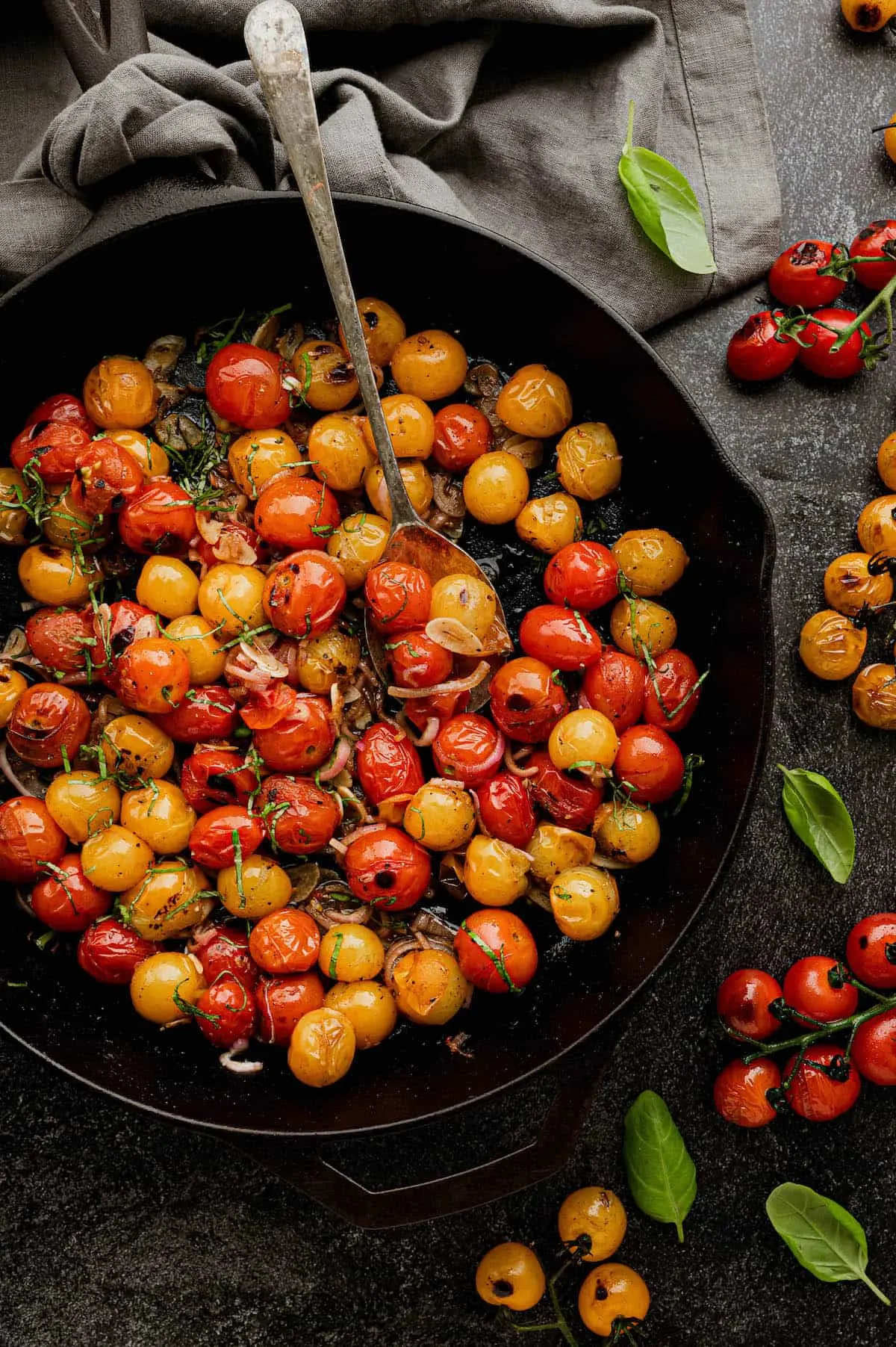 A cast iron pan full of blistered tomatoes.