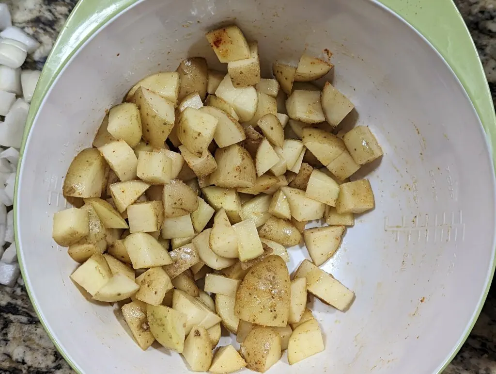 Cut up potatoes in a mixing bowl to make home fries.