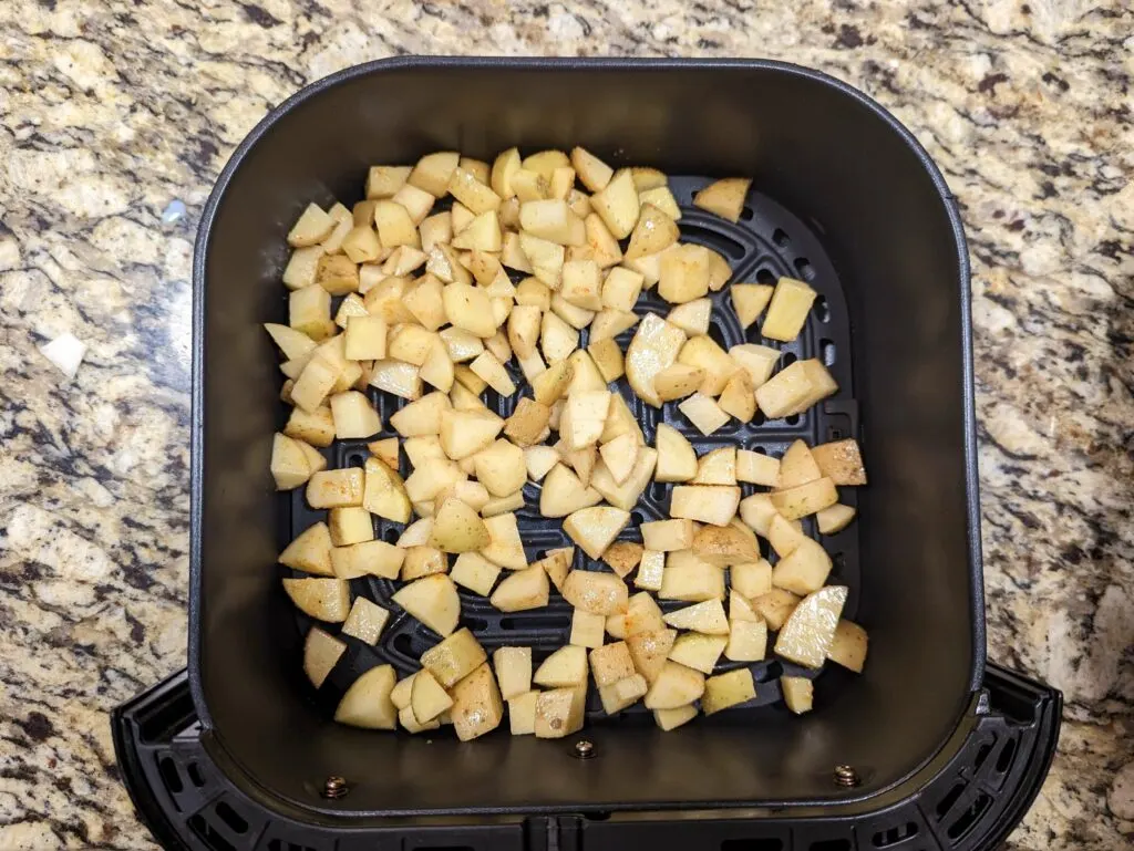 Home fries added to the air fryer basket.