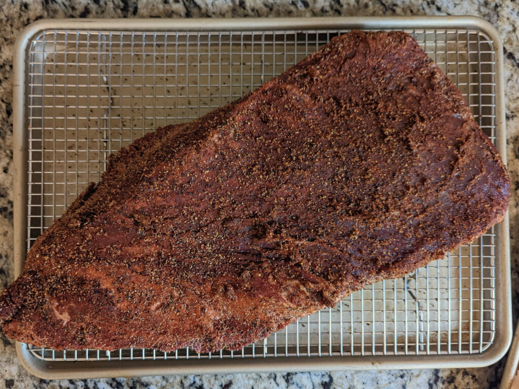 A seasoned and trimmed brisket on a wire rack.