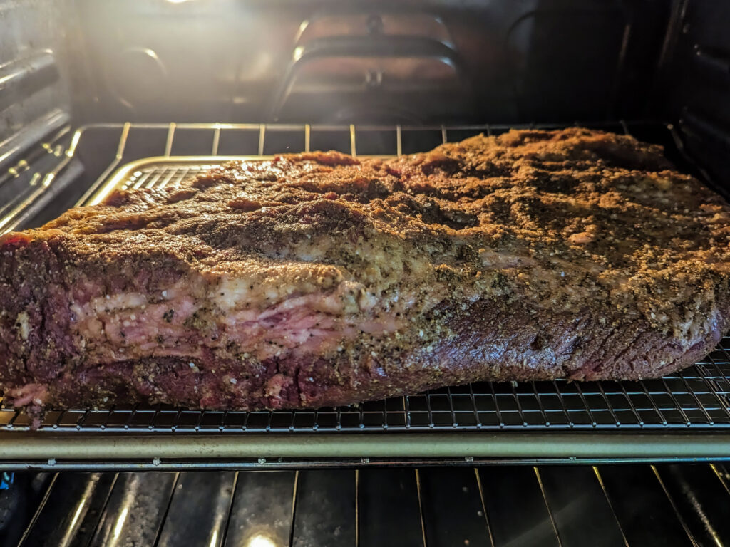 A brisket baking in the oven on a wire rack.