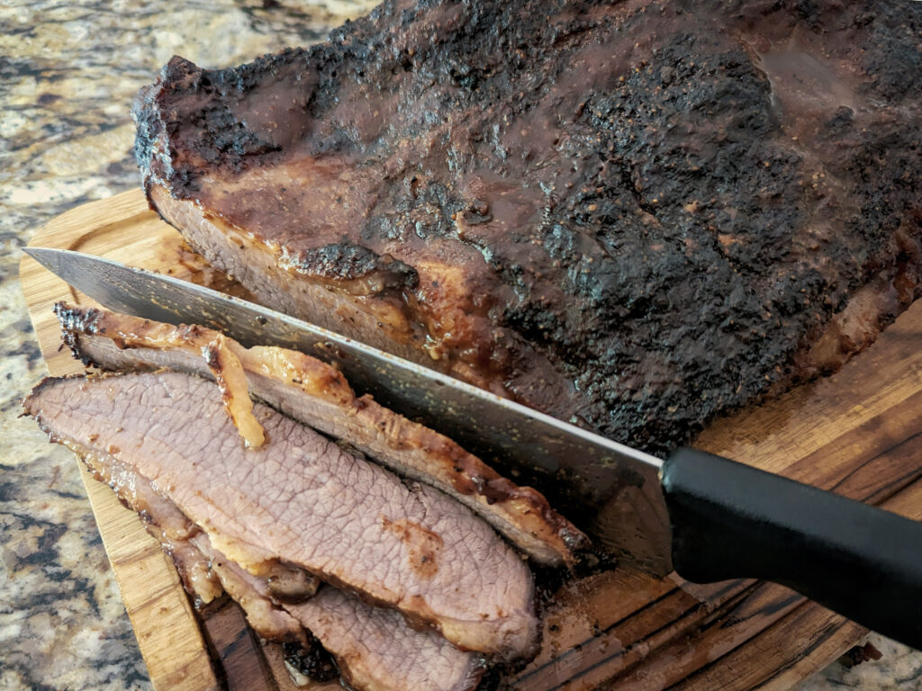 A knife cutting the brisket against the grain.