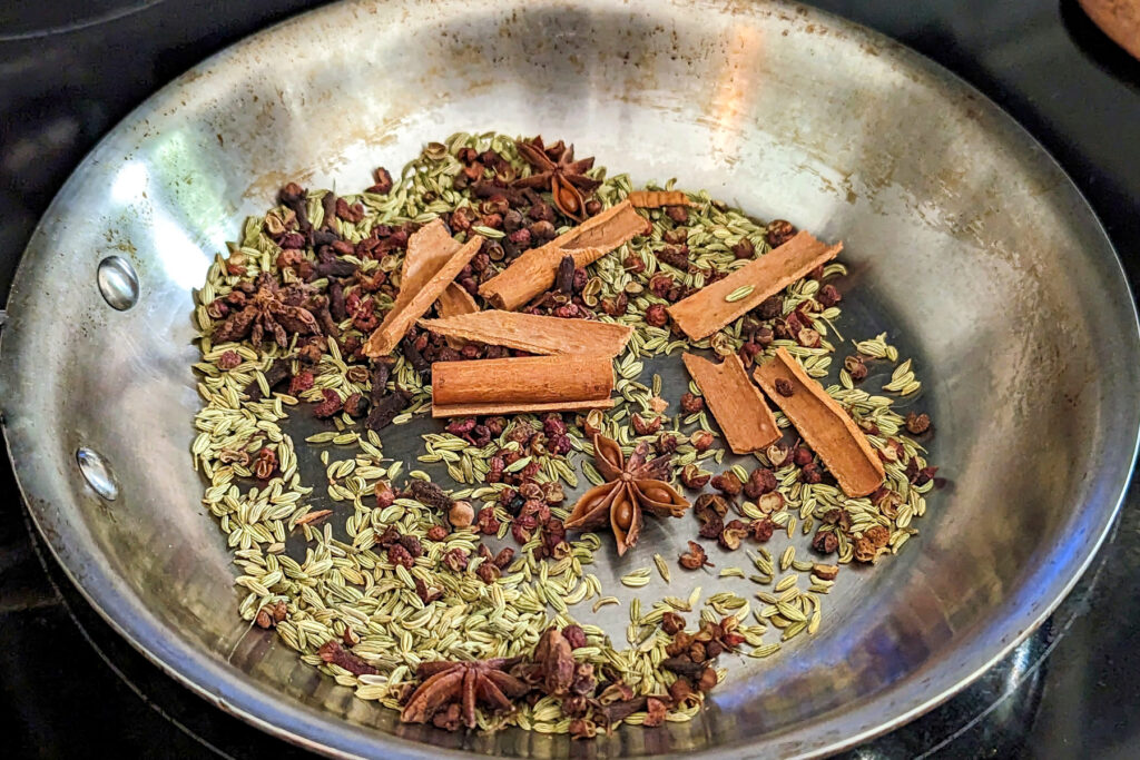 Whole spices toasting in a skillet.