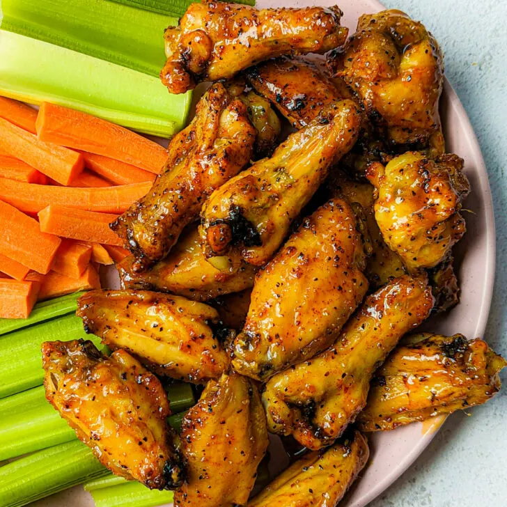Hot honey lemon pepper chicken wings on a plate with vegetables.