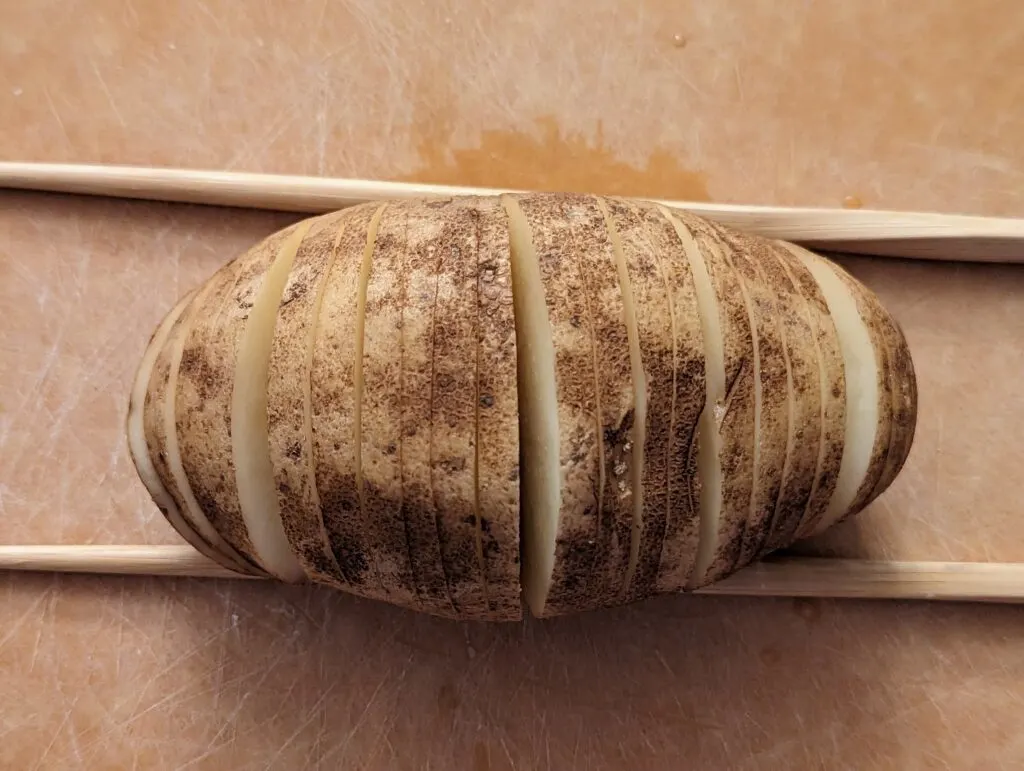 A sliced potato with two chopsticks on either side.