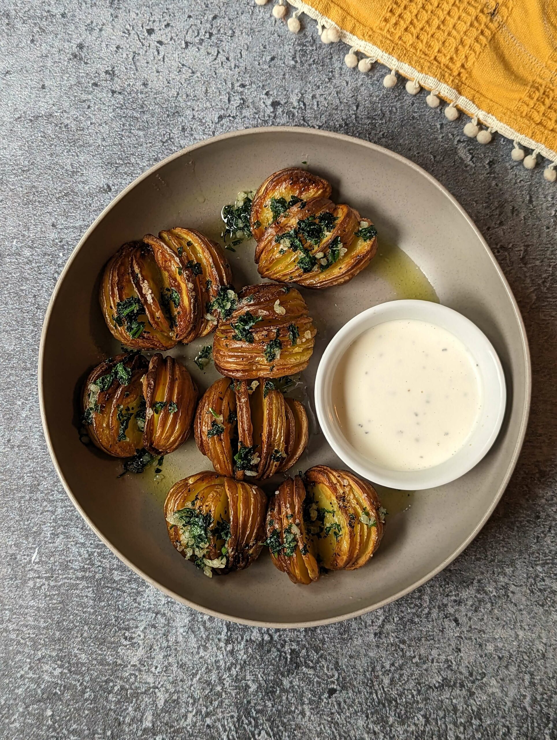 Air fryer hasselback potatoes garnished with garlic butter and served with ranch.
