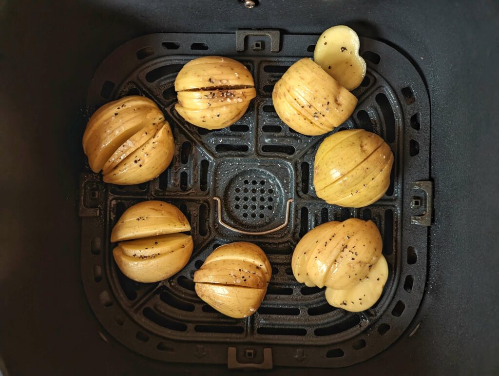 Hasselback potatoes lined into an air fryer basket.