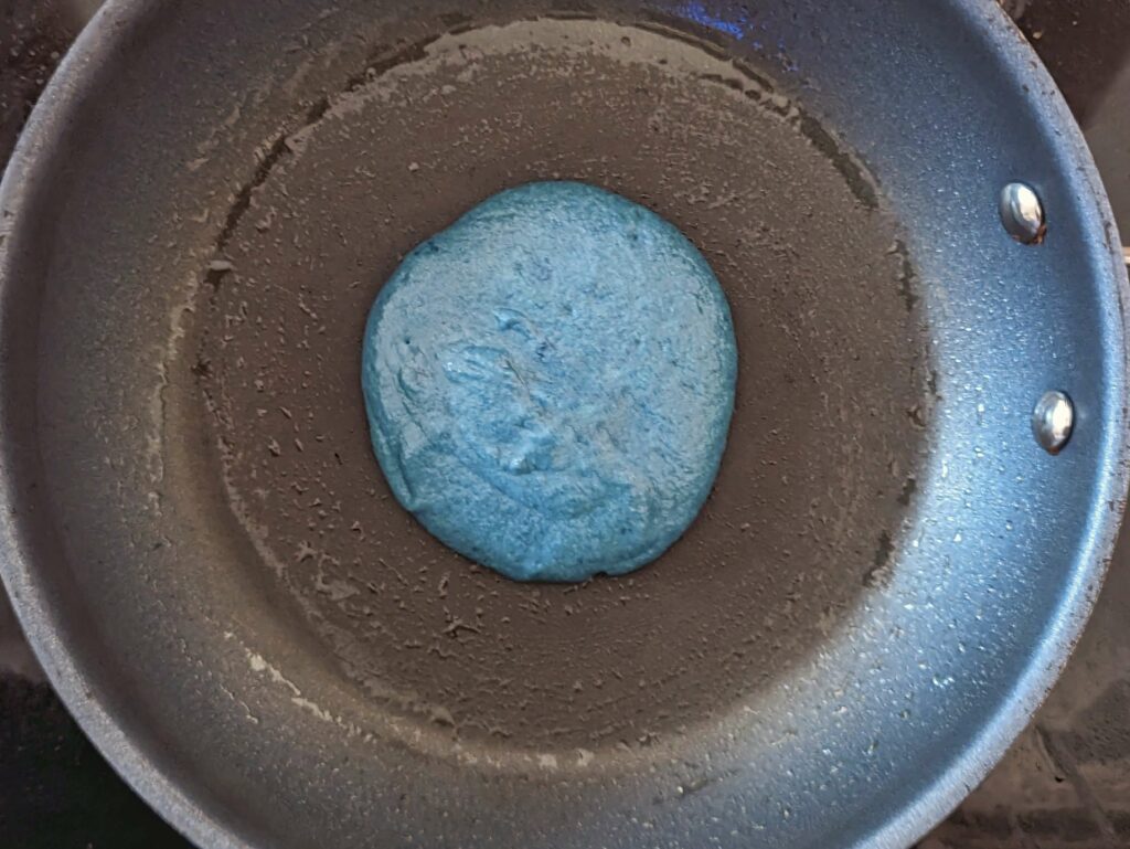 Pancake batter poured into the skillet to make a pancake.