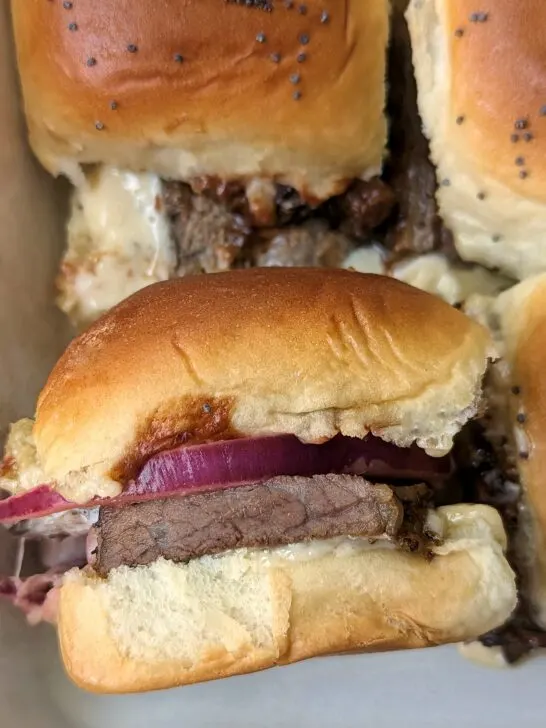 A side profile of the brisket sliders garnished with pickled onions.