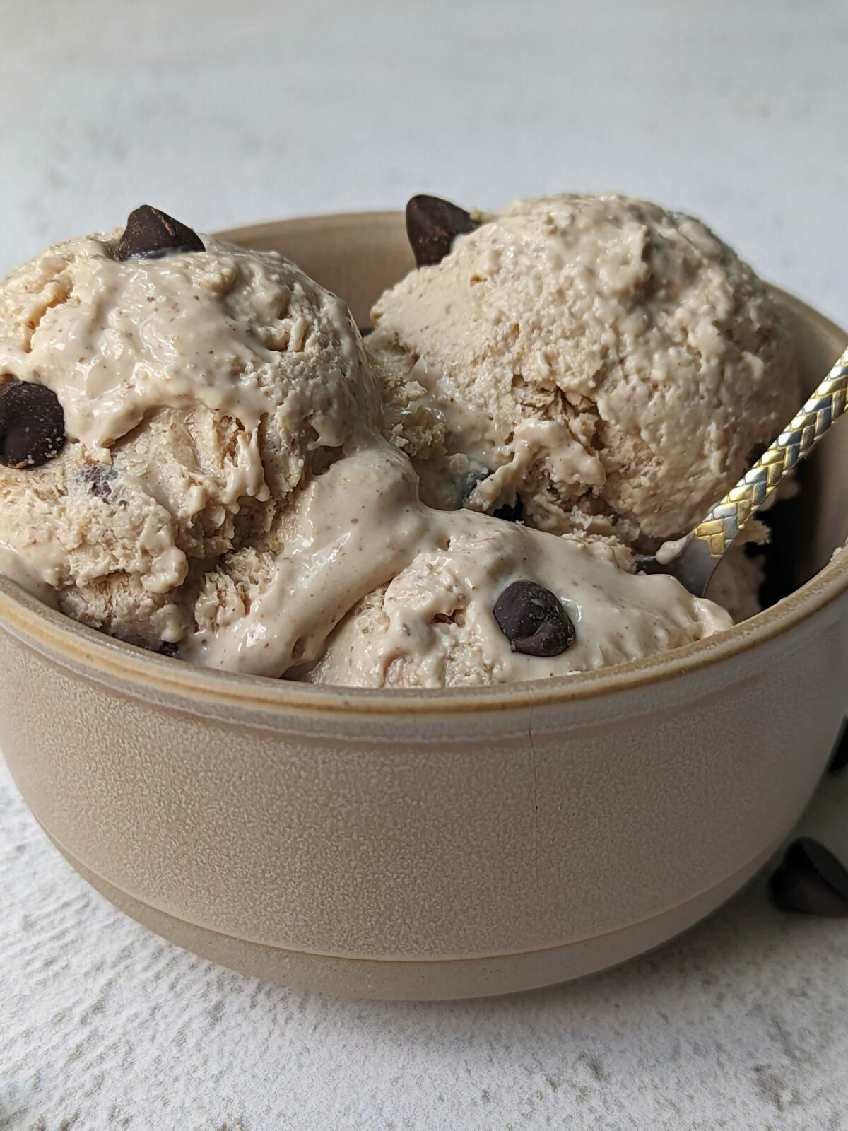 A bowl of cottage cheese ice cream garnished with and surrounded by chocolate chips.