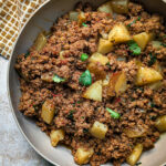 Picadillo con papas in a serving bowl and topped with fresh cilantro.