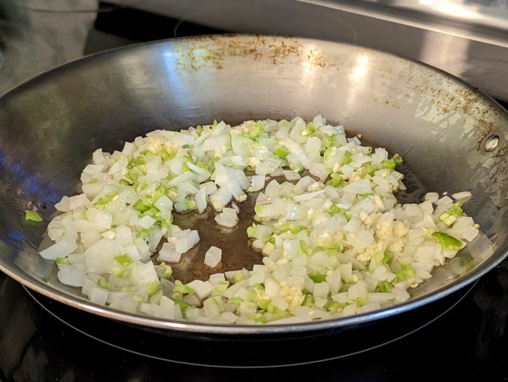 Onions, garlic, and chilies sautéing in a pan.