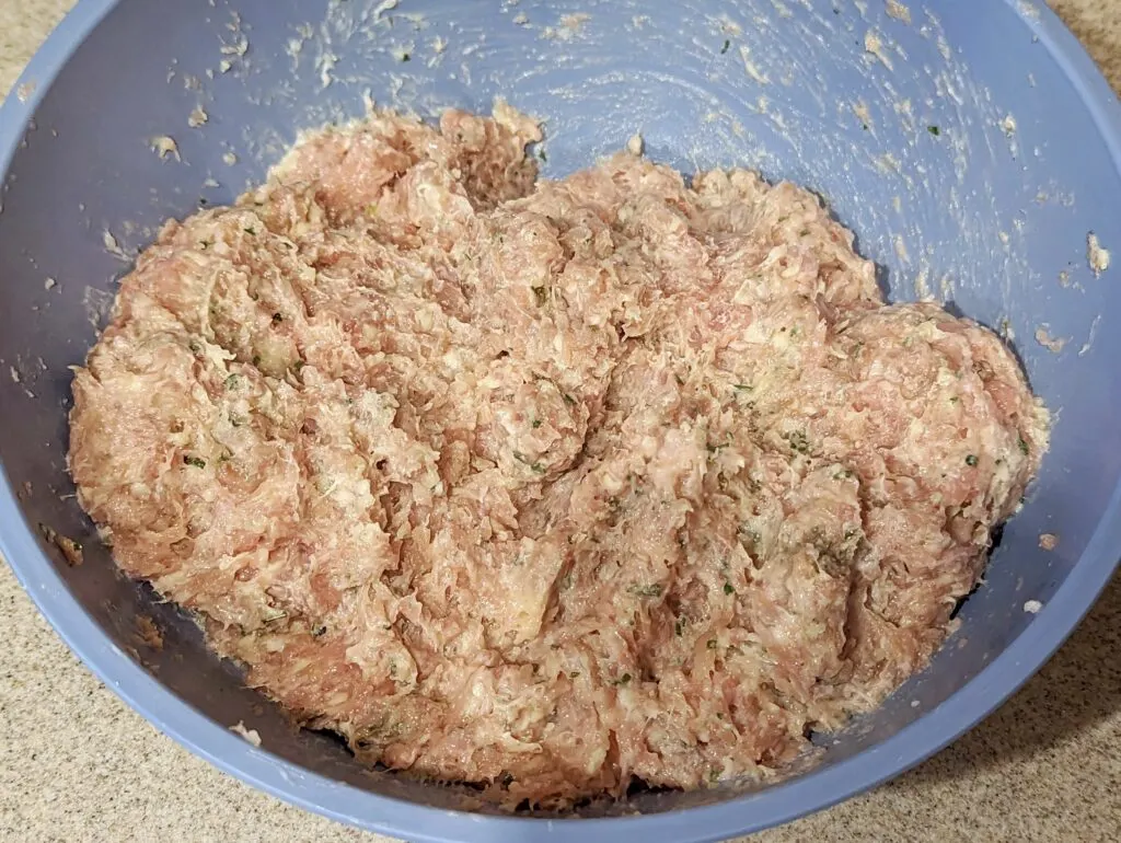 Ground chicken and other ingredients combined in a bowl.