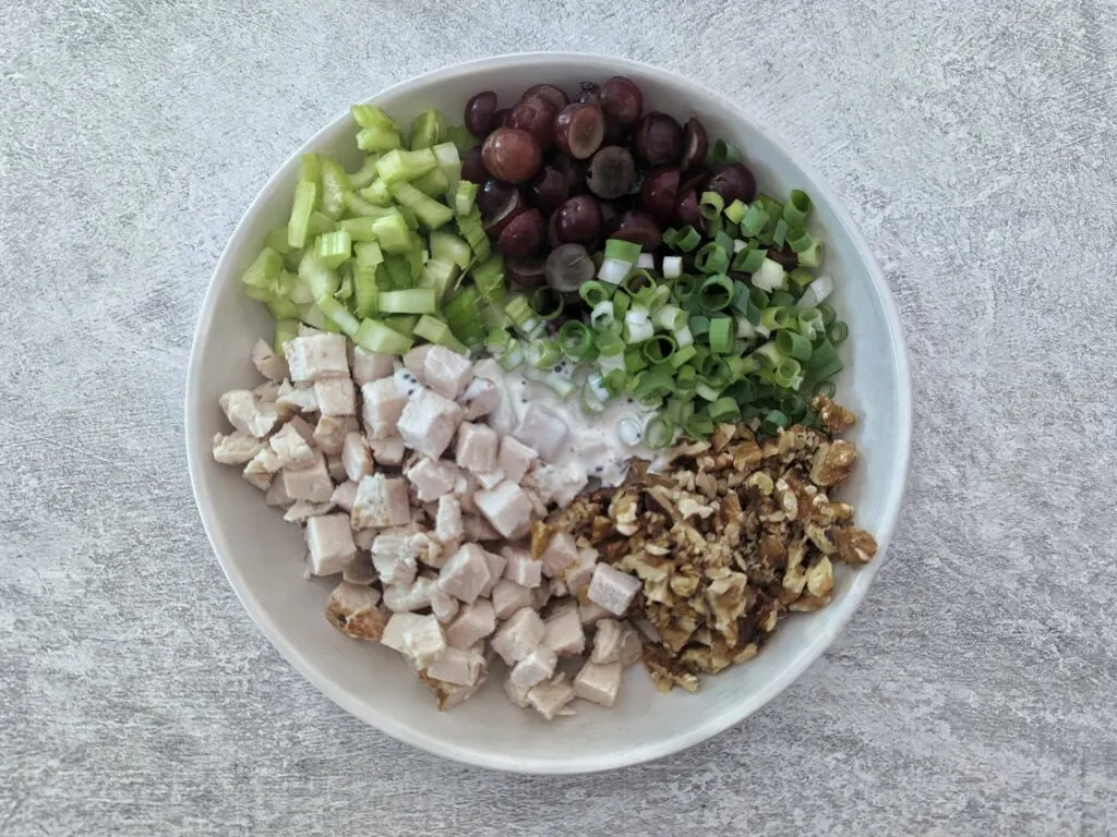 All of the chicken, vegetables, and dressing for the California chicken salad in a serving bowl. 