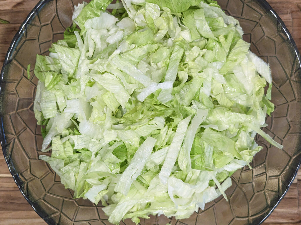Shredded lettuce in a mixing bowl.