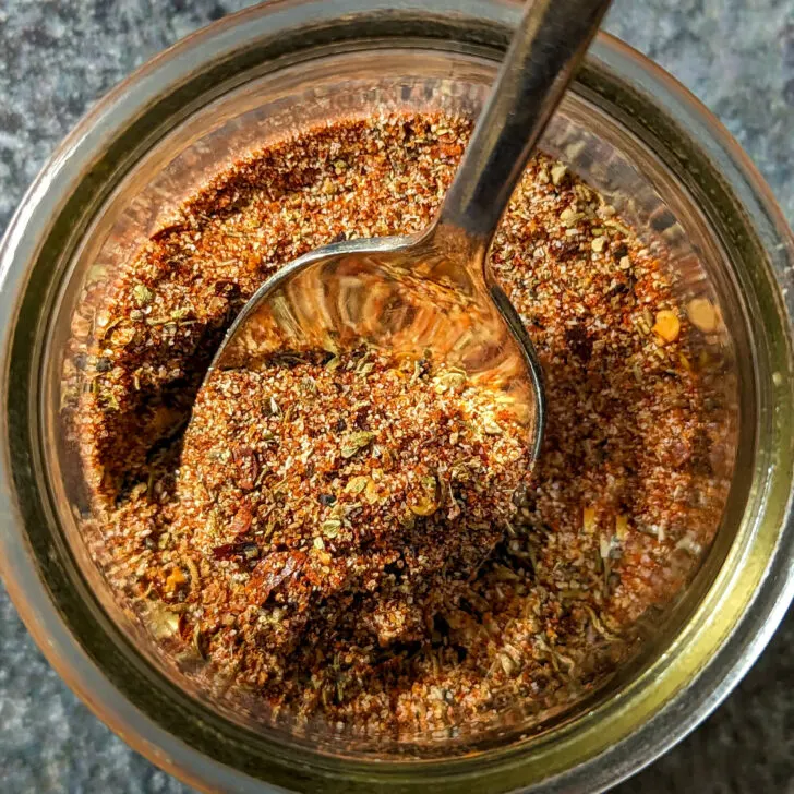 Slap Ya Mama Seasoning Recipe in a glass jar with a spoon in it.