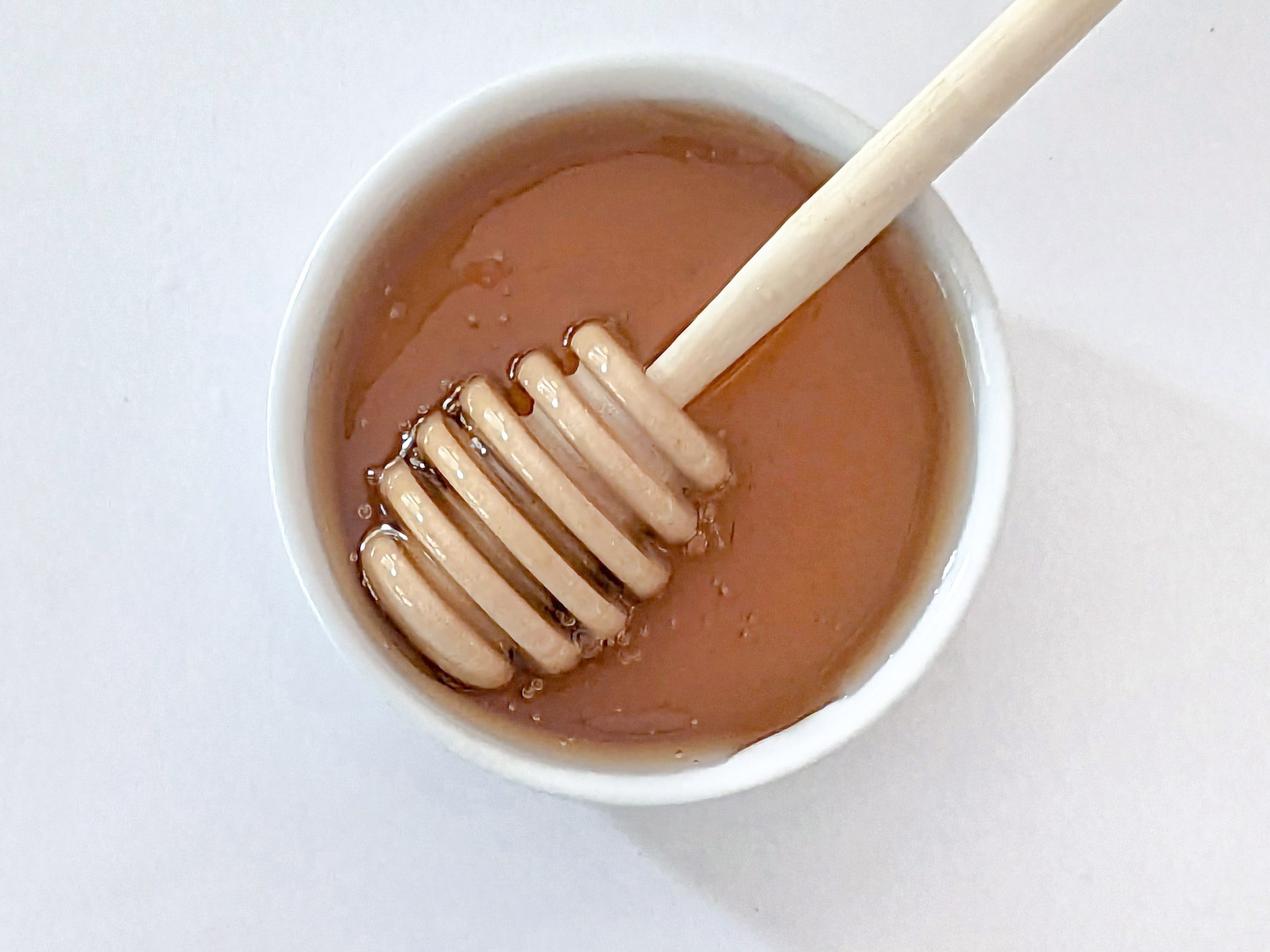 Honey in a small bowl with a honey stick in it.