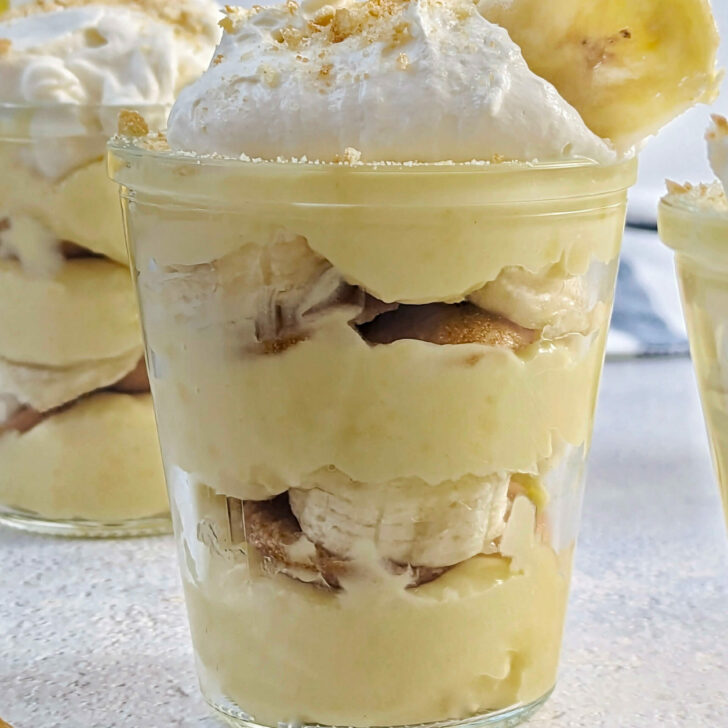 Banana pudding cups with whipped cream and crushed cookies.