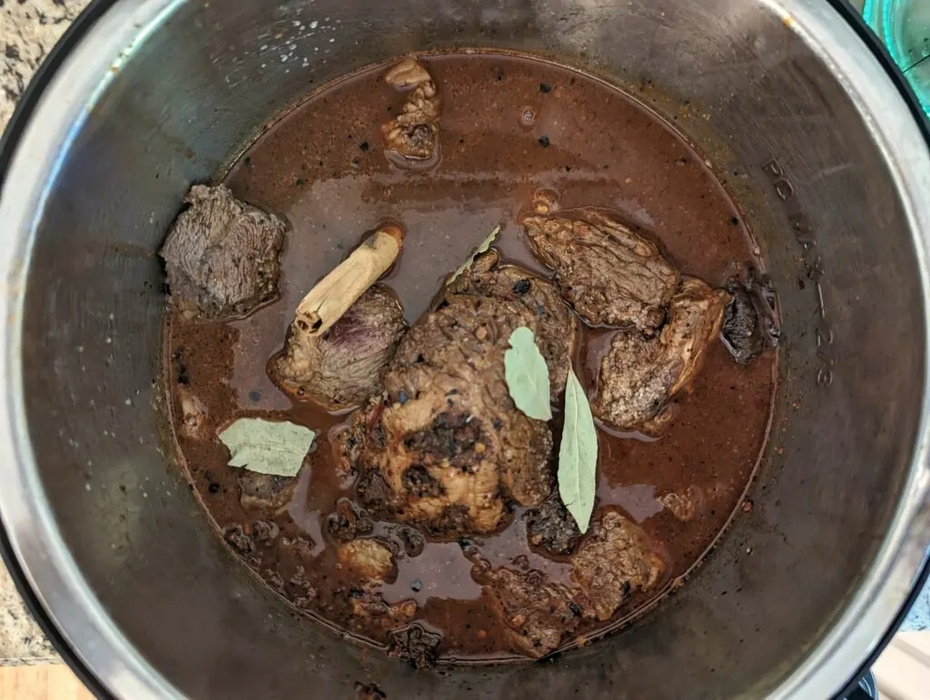 Bay leaves and cinnamon sticks added to the birria con consome in the instant pot.