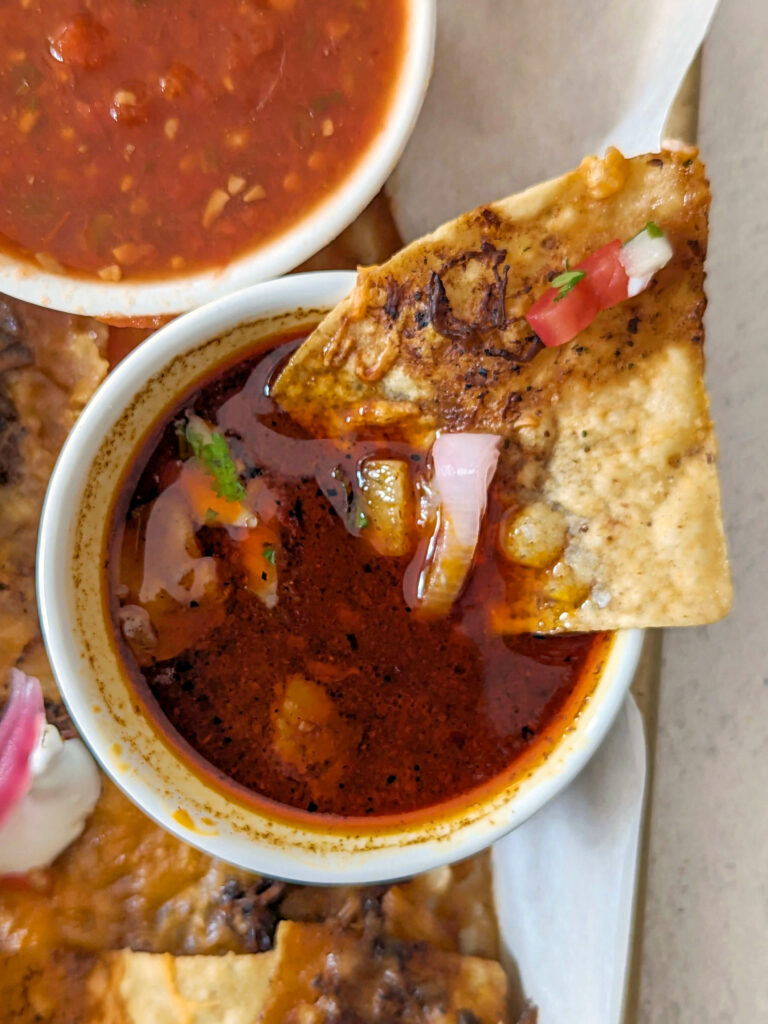 A chip of the birria nachos dipped in consome.
