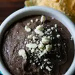 A bowl of black bean dip topped with cheese.