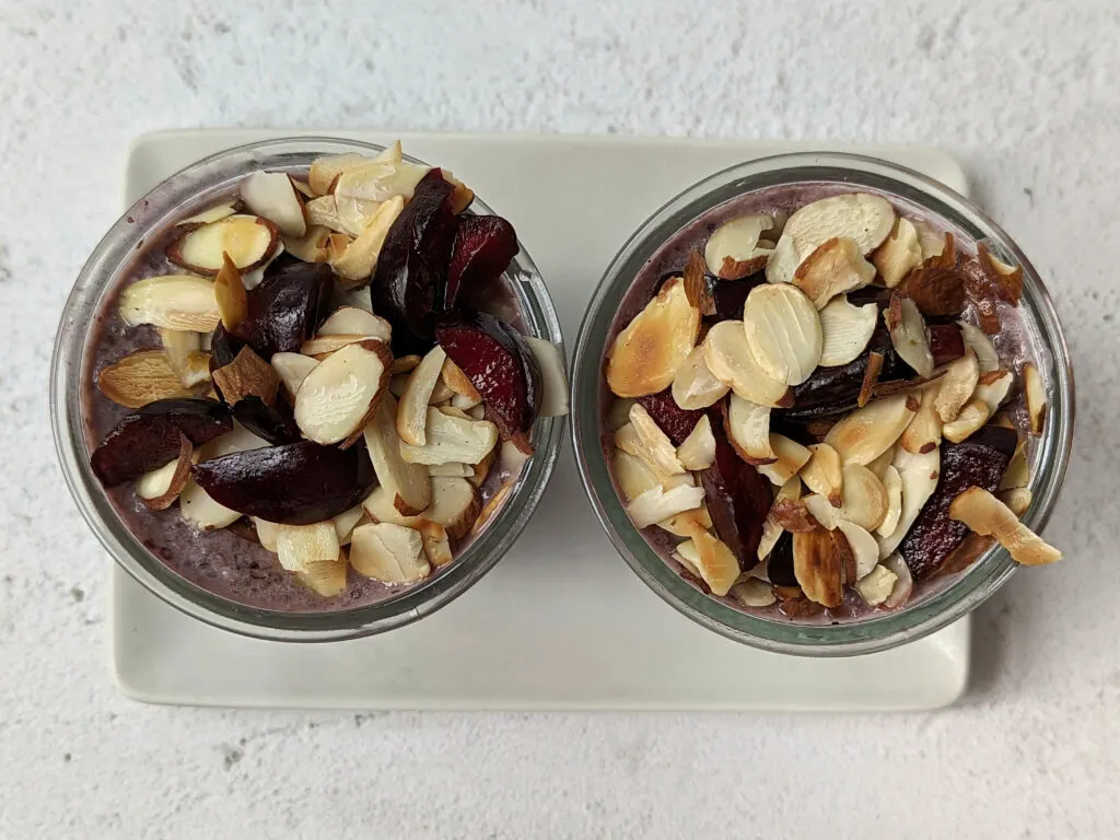 An overview of two containers of cherry overnight oats topped with toasted almonds and cherries.