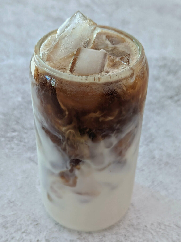 Cold brew added to the milk in a glass.