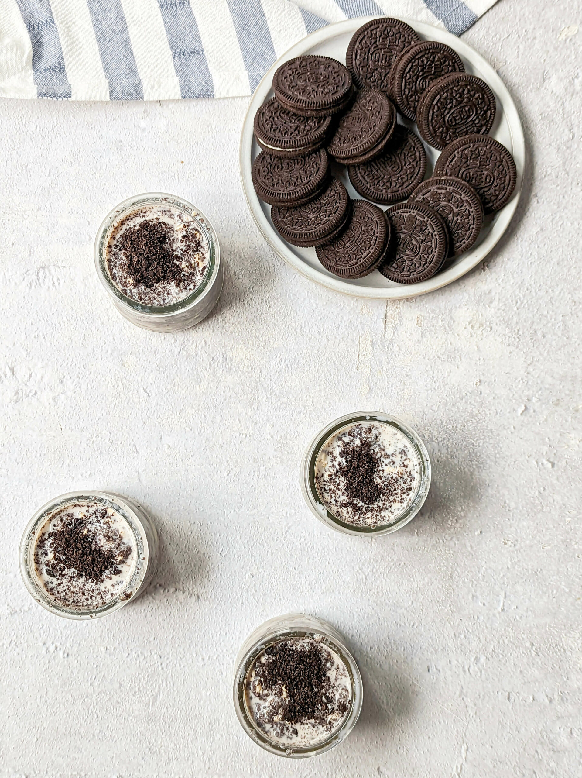 Four containers of oreo overnight oats with oreos on a plate.