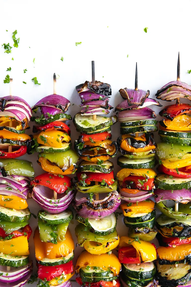 Colorful vegetable skewers lined onto a surface next to one another.