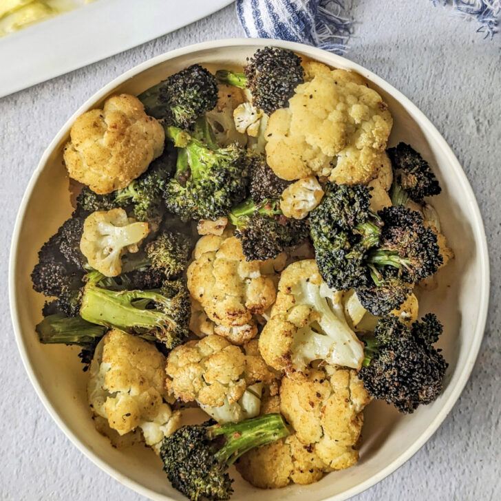 Air Fryer Broccoli and Cauliflower on a plate with a butter dish in the background.