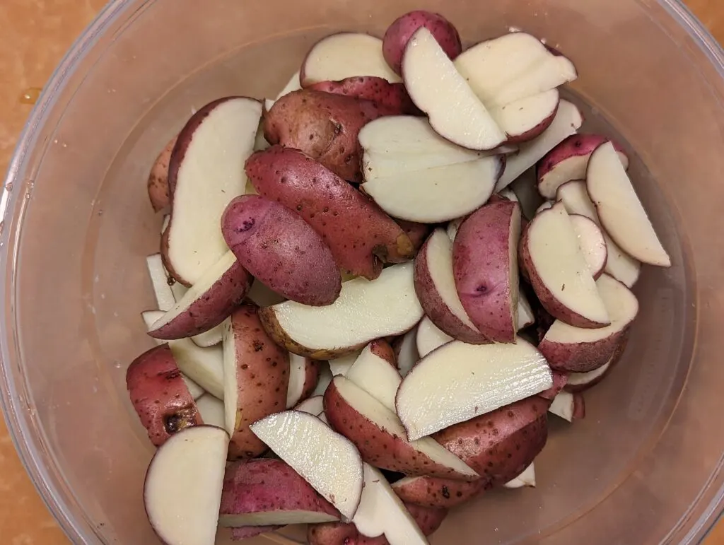 Red potato wedges in a mixing bowl. 