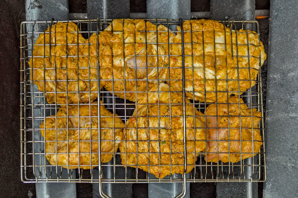 Chicken in a grill basket over the flavor bars.