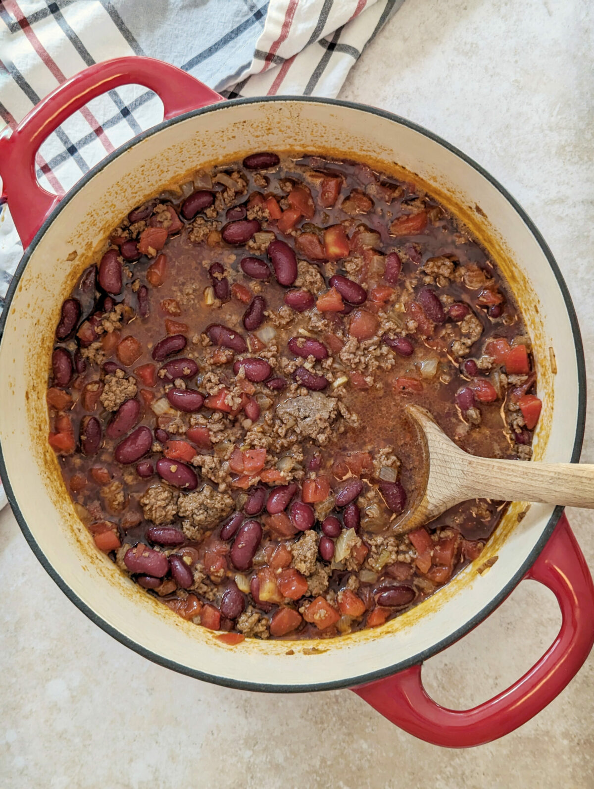 Dutch oven chili in a dutch oven with a spoon in it.