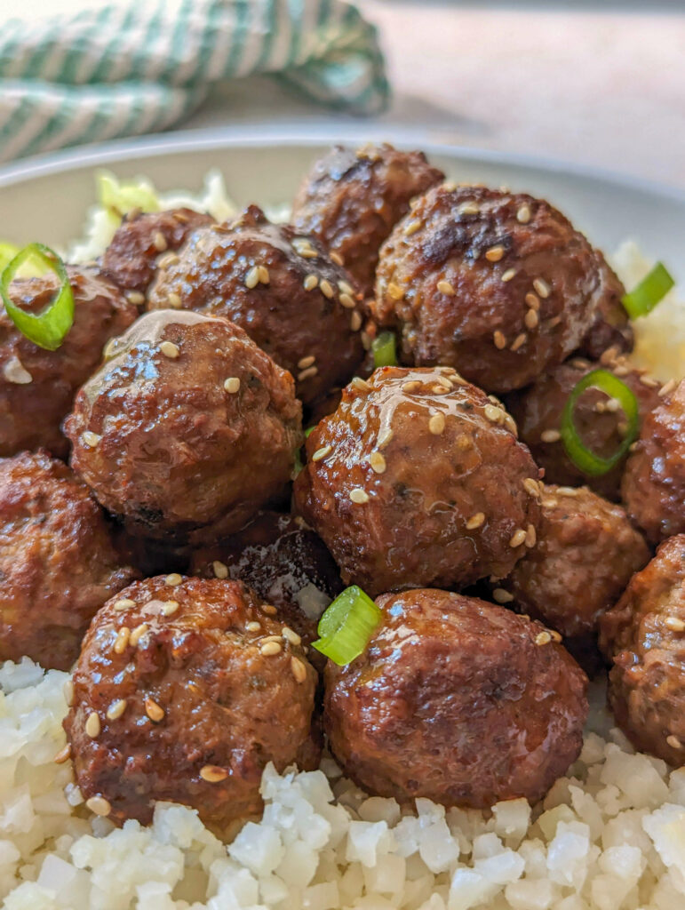 A close up of Instant pot frozen meatballs coated in teriyaki sauce and topped with scallions. 