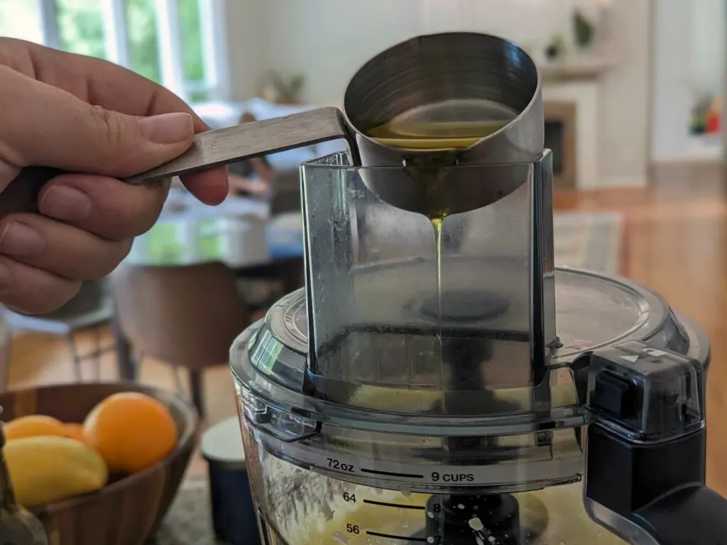 Olive oil being slowly added to the food processor.