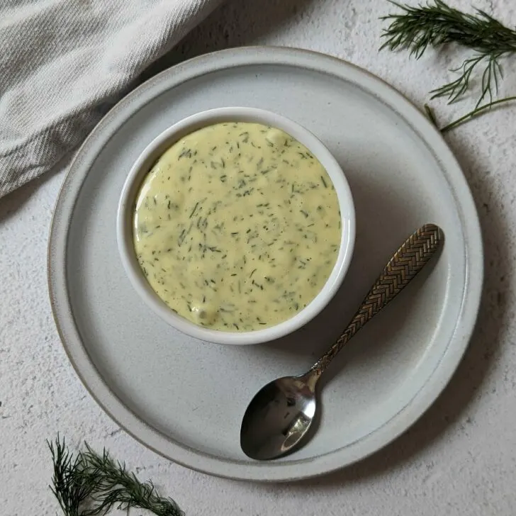 Lemon Dill Aioli in a small bowl with dill in the background.