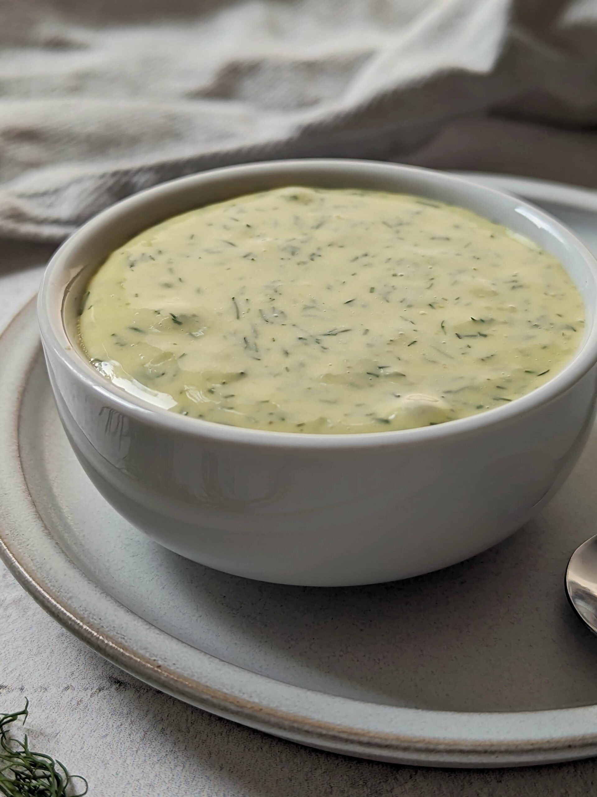 Lemon Dill Aioli in a small bowl with dill in the background.