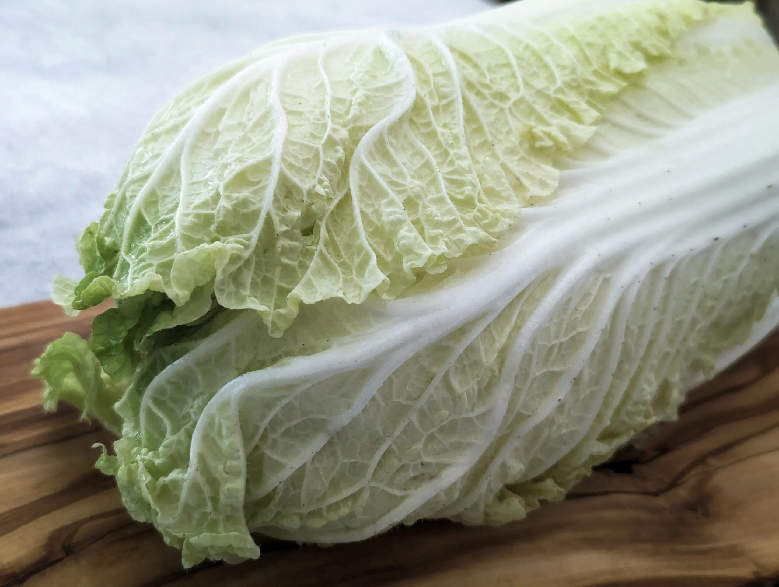 A side profile of a Napa cabbage on a cutting board.