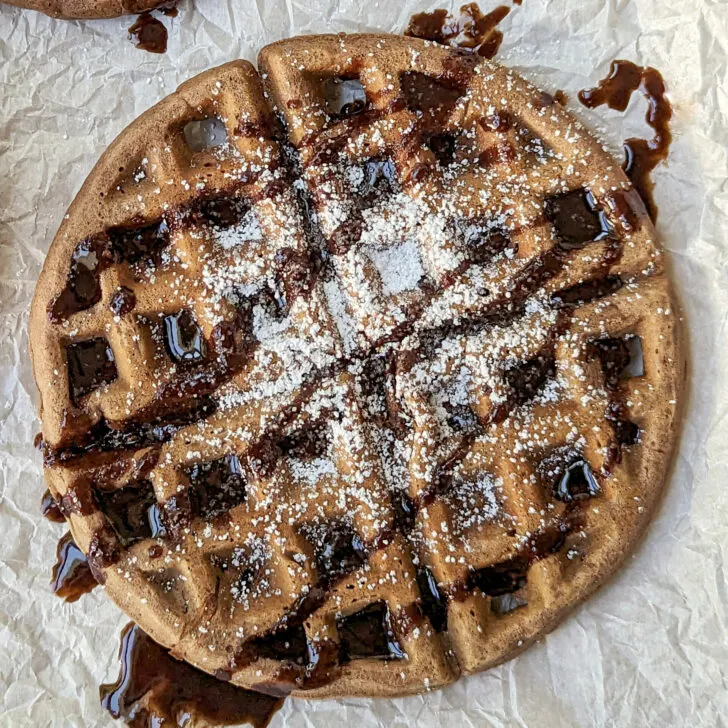 A nutella waffles topped with powdered sugar and chocolate sauce.