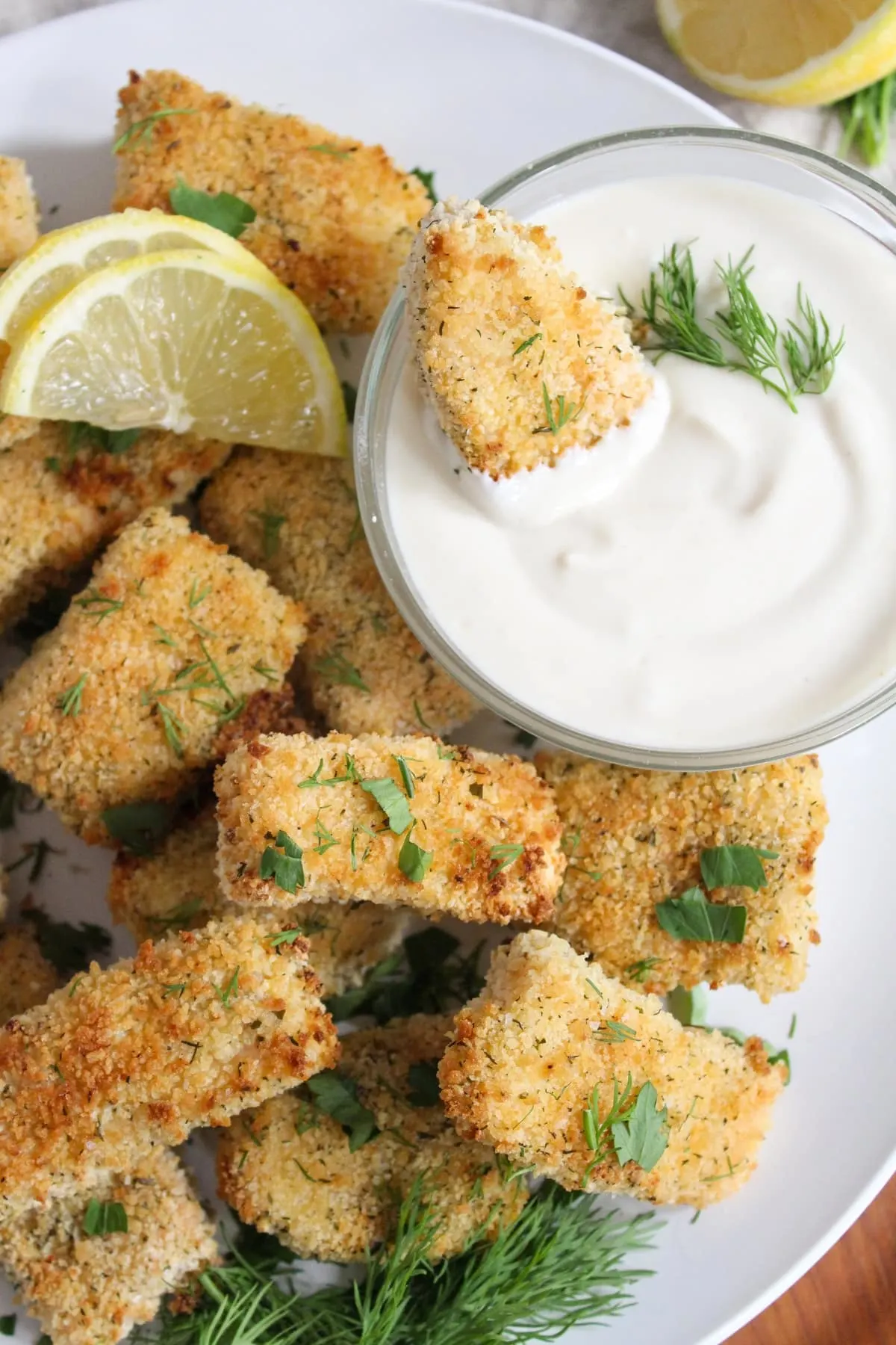 A creamy mustard sauce with a breaded dipping snack and lemons on the side.