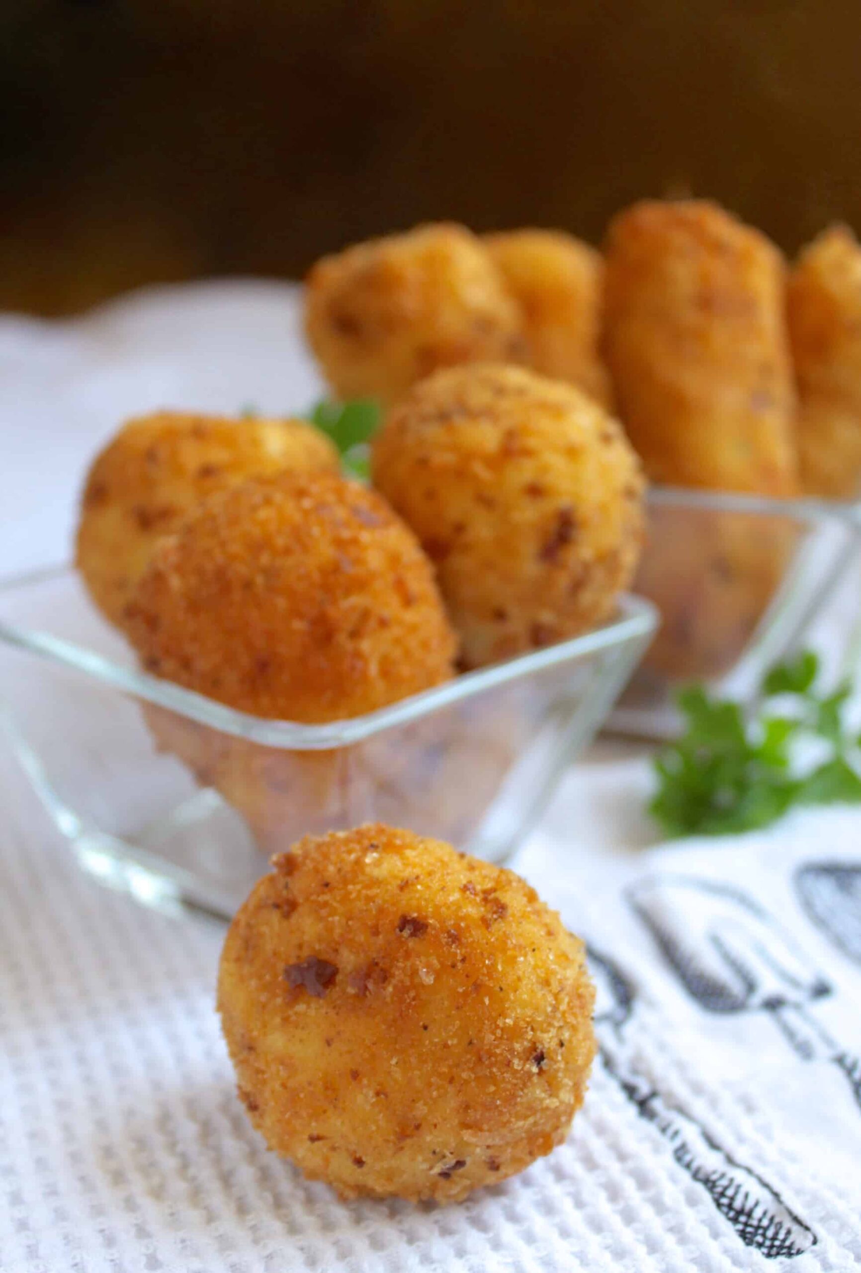 Potato Croquettes in a bowl with one on the table in front of the bowl.