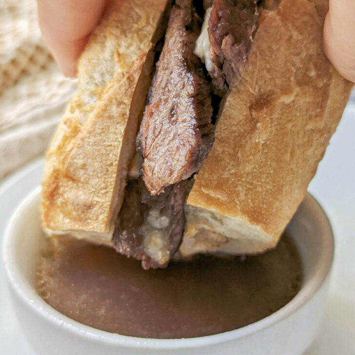 Air fryer french dips being dipped into au jus.