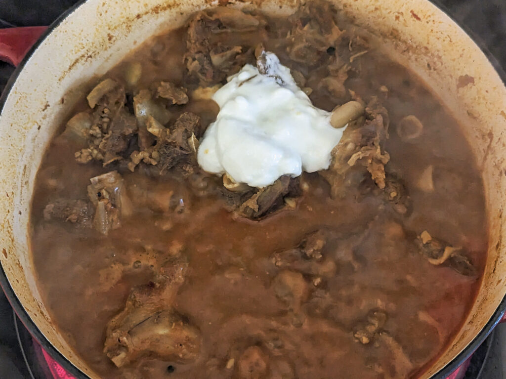 Yogurt added to the dutch oven brimming with stew.