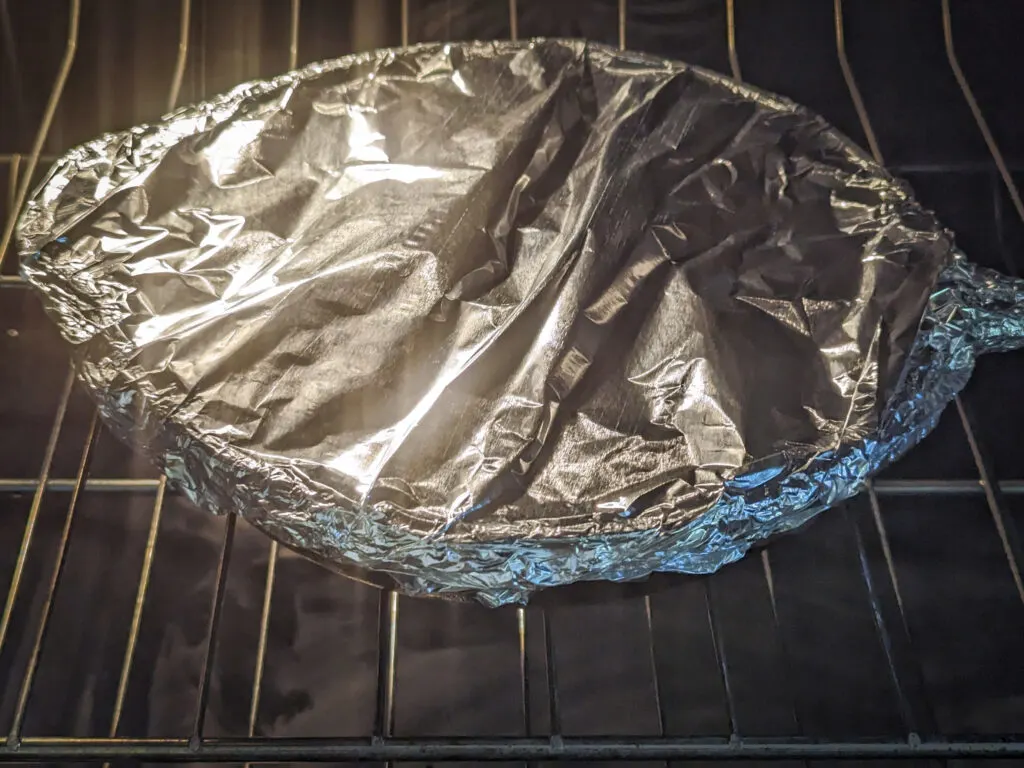 A skillet covered with foil in the oven.