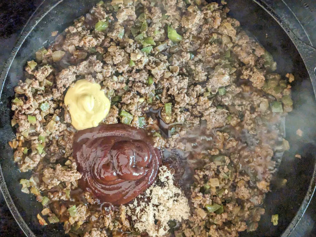 Mustard, BBQ sauce, brown sugar added to the skillet with the ground beef and vegetables.