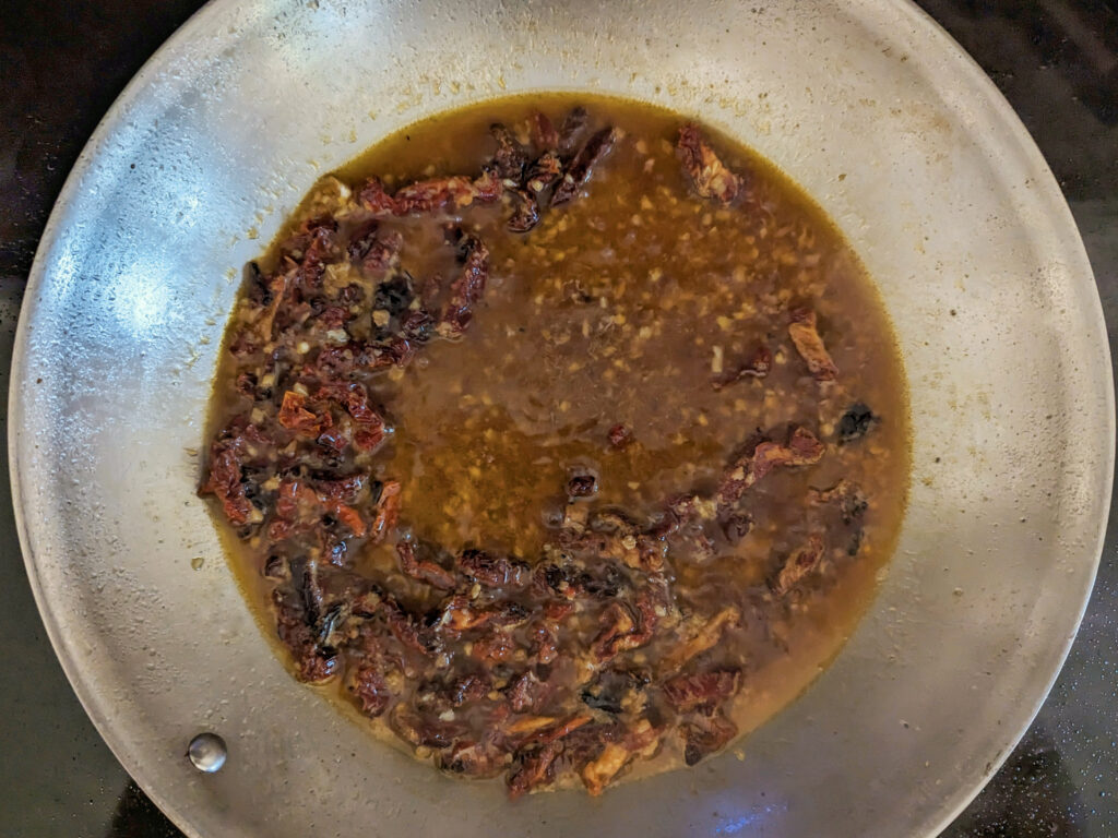 Chicken broth stirred into the skillet.